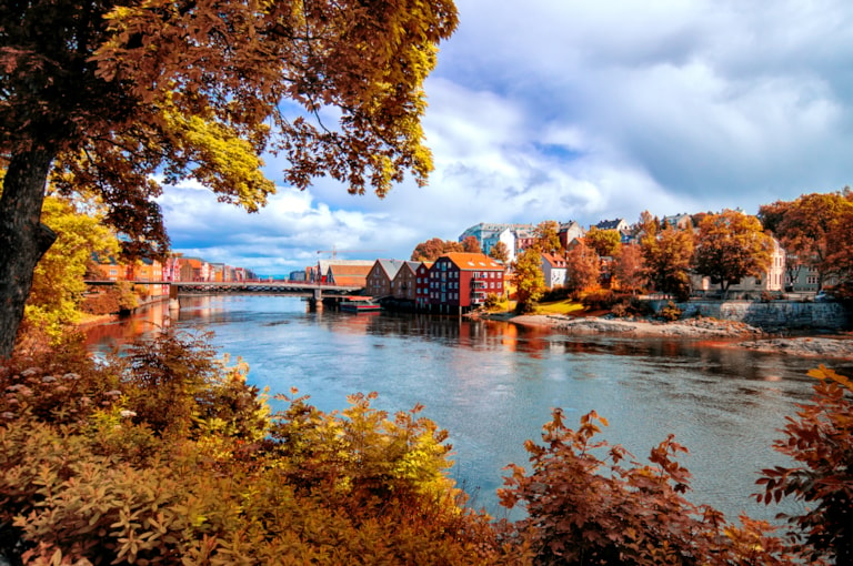 View through autumn foliage to Nidelva river, Trondheim city, Norway